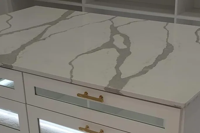 Veined stone slab countertop with brass pulls on a custom island